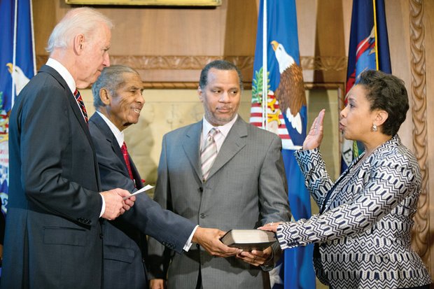 
Loretta Lynch is sworn in Monday by Vice President Joe Biden, left, as the new U.S. attorney general in a ceremony at the Justice Department. Her father, Lorenzo Lynch, second from left, and husband, Stephen Hargrove, proudly hold the Bible.