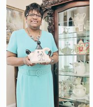 The Rev. Jeanette Brown displays one of the more than 100 colorful teapots at Harriet’s Place, the North Side home of Scripture Tea Fellowship Ministries.