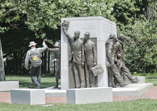 A passer-by gives a high-five to the likeness of Barbara Rose Johns at the Virginia Civil Rights Memorial at Capitol Square in Downtown. 
 Unveiled in 2008, the memorial celebrates Ms. Johns and others whose protests and lawsuits brought an end to the Jim Crow-mandated separation of black and white students in public schools. 
In 1951 at age 16, Ms. Johns led a student walkout from a decaying high school in Prince Edward County. The legal case that grew from that protest helped generate the U.S. Supreme Court’s landmark Brown v. Board of Education decision on May 17, 1954 — 61 years ago last Sunday.
That remarkable decision outlawed public school segregation and became a major step toward ending legal apartheid in this country.  
Other figures on the memorial include, front, the late NAACP attorneys Oliver W. Hill and Spottswood W. Robinson III, both of Richmond, who represented Ms. Johns and others in Prince Edward County and whose legal attack on segregation became part of the Brown case. Right, figures celebrate courageous Virginians who marched, protested and helped bring down segregation, serving as a reminder of the role of ordinary citizens in shaping public policy.