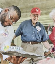 
FeedMore Chef Amory M. James presents 102-year-old Helen Heinzen of the Lakeside community in Henrico County on Tuesday with the 7 millionth meal delivered by Meals on Wheels of Central Virginia as her son looks on.