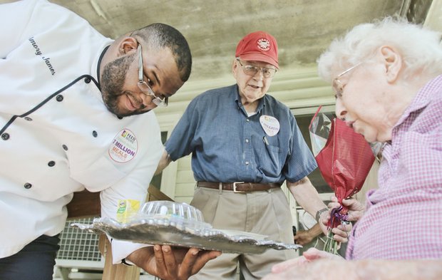 FeedMore Chef Amory M. James presents 102-year-old Helen Heinzen of the Lakeside community in Henrico County on Tuesday with the 7 millionth meal delivered by Meals on Wheels of Central Virginia as her son looks on.
