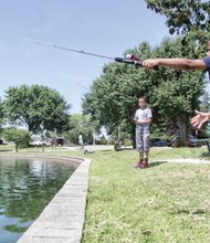 At Fountain Lake in Byrd Park, Kyjuan Ross, 9, looks on as his 5-year-old cousin, Nahjir King, casts his fishing line.
