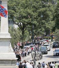 The Confederate battle flag, a symbol of racial hate, ironically waves Wednesday over the horse-drawn carriage bearing the casket of beloved African-American minister and state Sen. Clementa C. Pinckney to the South Carolina State Capitol in Columbia, where he will lie in state. 