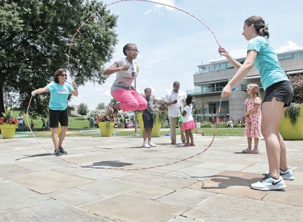 Indacia Turner, 11, shows off her skills in Double Dutch jump roping as Gail Kingrey and Abbie Dentler of the Swingers Jump Rope Team handle the ropes at the museum’s Pauley Center Patio. Other activities included interactive games, creating Egungun-inspired masks and a musical performance by the Afrika Arkestra.  