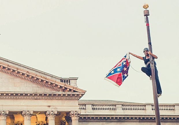 Bree Newsome boldly holds the Confederate flag after climbing the flagpole at the Statehouse in Columbia, S.C., to take it down last Saturday.