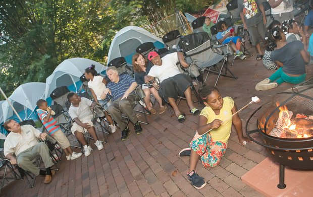 CITYSCAPE-Slices of life and scenes in Richmond. - Nine-year-old Nysia Harris toasts a marshmallow at the inaugural Capital Campout on the grounds of the Governor’s Mansion last Thursday. Behind her, Gov. Terry McAuliffe, center, chats with other youngsters attending the overnight campout sponsored by the Virginia State Parks. The governor and First Lady Dorothy McAuliffe hosted dozens of children from Richmond area Boys & Girls Clubs at the event promoting state parks and outdoor fun as part of National Great Outdoors Month. Mrs. McAuliffe also took the youngsters to the James River to fish, hike and kayak. The children ate dinner and then spent the night in tents on the mansion grounds.