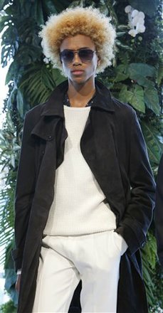 A model wears a midnight blue coat over white sweater with white trousers during the Tommy Hilfiger presentation at Men's Fashion Week in New York, Wednesday, July 15, 2015. 