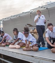 Food, fun and games for National Night Out- Children learn how to perform CPR as the song “Stayin’ Alive” from the motion picture “Saturday Night Fever” plays in the background.
