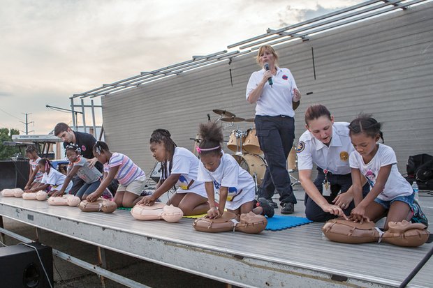 Food, fun and games for National Night Out- Children learn how to perform CPR as the song “Stayin’ Alive” from the motion picture “Saturday Night Fever” plays in the background.
