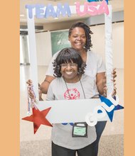 
Mary Davis, front, enjoys an Olympic hero’s welcome Monday night when she arrives home at Richmond International Airport. Among the bevy of family and friends greeting her was counselor Keisha Walker. Left, friends hold a sign to show their pride in Team Virginia’s medal-winning efforts.