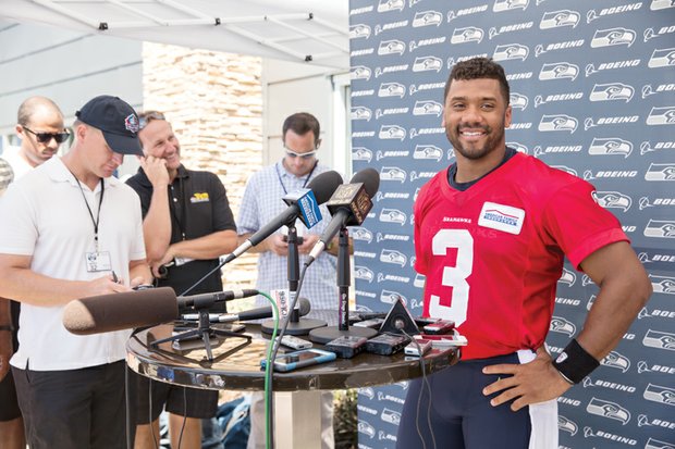 Seahawks quarterback Russell Wilson is all smiles at a training camp news conference last week following the announcement of successful negotiations extending Wilson’s contract with Seattle through 2019.