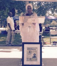 Storyteller Mama Edie salutes black firefighters. A framed Chicago Citizen Newspaper article about the event is posted below the speaker's stand.