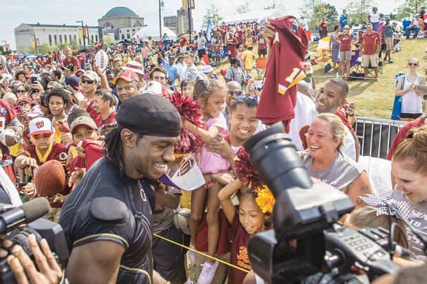 Washington quarterback Robert Griffin III, aka RGIII, greets well-wishers Saturday at Fan Appreciation Day at the team’s training camp behind the Science Museum of Virginia. Clockwise from top right, Tatum Johnson, 7, gets a better look by riding the shoulders of her father, Bill Johnson. 