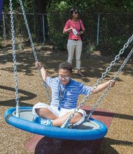 Fun at ARCpark- Joshua Parson, 11, enjoys a swing with his mother, Natalia Parson, nearby. The 2.4-acre park is open daily from dawn to dusk. It is the first recreation area designed to accommodate persons with disabilities in Central Virginia, according to Greater Richmond ARC, and includes a wheelchair-accessible tree house and fitness equipment. The park borders the organization’s headquarters at 3600 Saunders Ave.