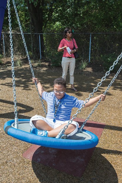 Fun at ARCpark- Joshua Parson, 11, enjoys a swing with his mother, Natalia Parson, nearby. The 2.4-acre park is open daily from dawn to dusk. It is the first recreation area designed to accommodate persons with disabilities in Central Virginia, according to Greater Richmond ARC, and includes a wheelchair-accessible tree house and fitness equipment. The park borders the organization’s headquarters at 3600 Saunders Ave.