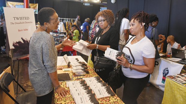 Happily natural - Valerie Ashe, left, discusses her husband Bert Ashe’s book, “Twisted: My Dreadlock Chronicles,” with Gigi Garnett, center, and Dina Elliott last Saturday at the 13th Annual Happily Natural Day at Plant Zero on South Side. 