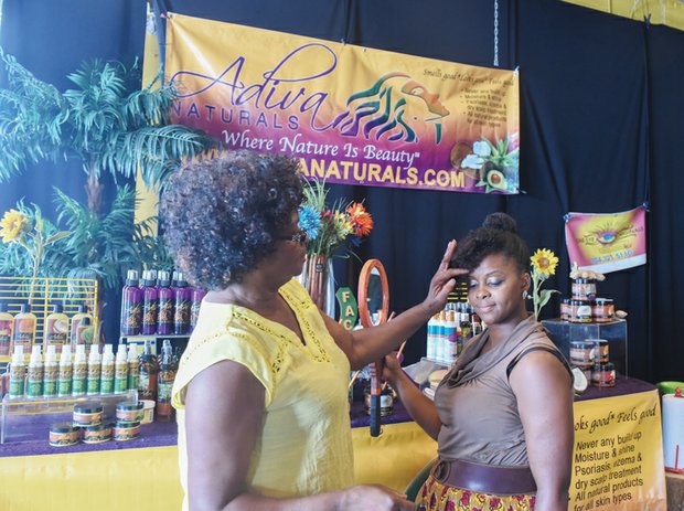 Happily Natural- Lucenia Thomas with Adiva Naturals products shows Tanetta Caleb the finer points and benefits of a hair care product. The two-day event is a business expo, cultural arts and crafts trade show designed to promote holistic health and social change. It also features performances by hip-hop, soul and spoken word artists.