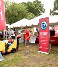 Com-Ed displays their ice box race car and little Jeremy Powell for festival goers. ComEd’s Patrick Grave gives the youngster tips.