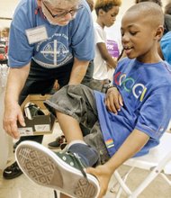 Well-heeled, ready for school- Deontay Wilkerson tries on new Converse sneakers Monday at Second Baptist Church on South Side with the help of volunteer Rugby Baker.