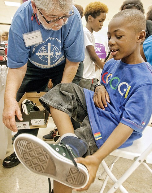 Well-heeled, ready for school- Deontay Wilkerson tries on new Converse sneakers Monday at Second Baptist Church on South Side with the help of volunteer Rugby Baker.