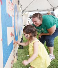 3-year-old Harper Tysall leaves her artistic mark on an equality mural with guidance from Amy Roberts.