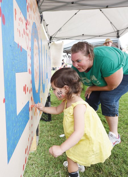 3-year-old Harper Tysall leaves her artistic mark on an equality mural with guidance from Amy Roberts.