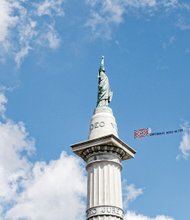 A plane flies above protesters at the Jefferson Davis monument on Monument Avenue with a trailing Confederate flag and a misspelled counter-protest message that “Confederate Heros (sic) Matter.”