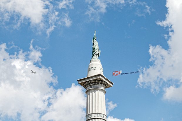 A plane flies above protesters at the Jefferson Davis monument on Monument Avenue with a trailing Confederate flag and a misspelled counter-protest message that “Confederate Heros (sic) Matter.”