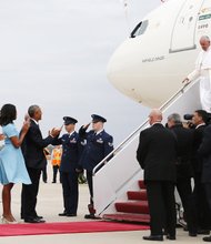 Pope Francis, right, receives a presidential welcome as he arrives Tuesday at Joint Base Andrews outside Washington. President Obama, First Lady Michelle Obama, and their daughters, Sasha and Malia, applaud as the pontiff comes down the steps.