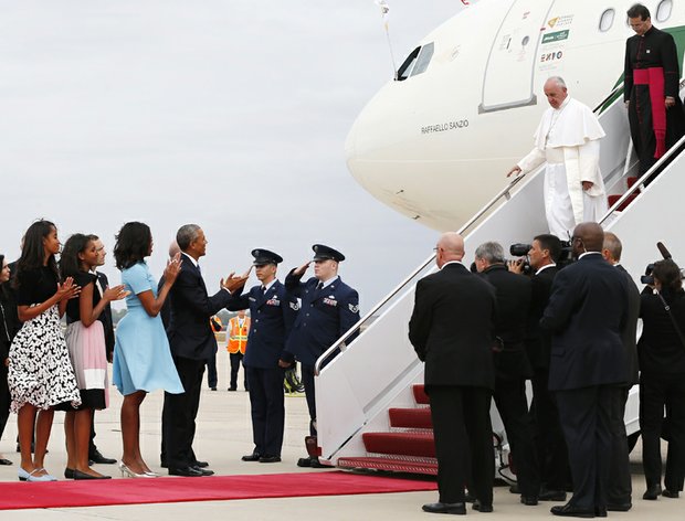 Pope Francis, right, receives a presidential welcome as he arrives Tuesday at Joint Base Andrews outside Washington. President Obama, First Lady Michelle Obama, and their daughters, Sasha and Malia, applaud as the pontiff comes down the steps.