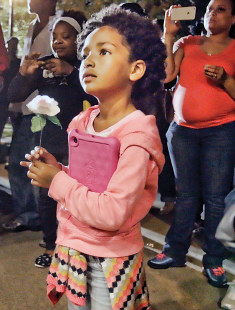 A show of love // 
Ama Aghomo holds a rose during the prayer vigil for Richmond’s “Ambassador of Compassion” Alicia C. Rasin at Jefferson Park in Church Hill. About 100 people gathered Oct. 15 to remember Ms. Rasin, who died Oct. 9. For more than two decades, Ms. Raisin organized prayer vigils for families of homicide victims in the city. She also provided food and clothes to the needy and gave gifts to children. 