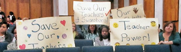 Teachers at Monday’s Richmond School Board meeting hold signs showing their opposition to the school administration’s plan to move some elementary school teachers from their current classrooms to other schools. 