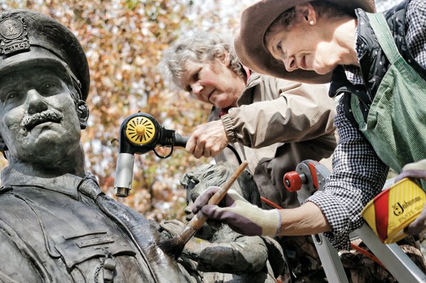 Lynda Solansky, left, and sculptor Maria J. Kirby-Smith clean the bronze Richmond Police Memorial statue in Nina F. Abady Festival Park beside the Richmond Coliseum. 
Ms. Kirby-Smith created the 8½-foot-tall statue that was placed in 1987 and pays homage to city police officers and the 28 killed in the line of duty between 1869 and 2003. A private foundation paid for the statue that depicts an officer carrying a child down steps. The artist and her friend drove up from South Carolina to wash and wax the statue Tuesday, possibly the statue’s first cleaning since it was dedicated 28 years ago. 
The cleaning was done ahead of a wreath-laying ceremony that Mayor Dwight C. Jones will lead Tuesday, Nov. 24, according to retired Officer Glenwood W. Burley, the statue’s protector. He’s now leading a push to win city approval to move the statue from its home on the 7th Street side of the park to The Carillon area of Byrd Park. 
The Carillon Civic Association, which represents people living next to the park, has publicly expressed opposition, arguing the statue would be out of place and urging city leaders to find a more suitable location. 
