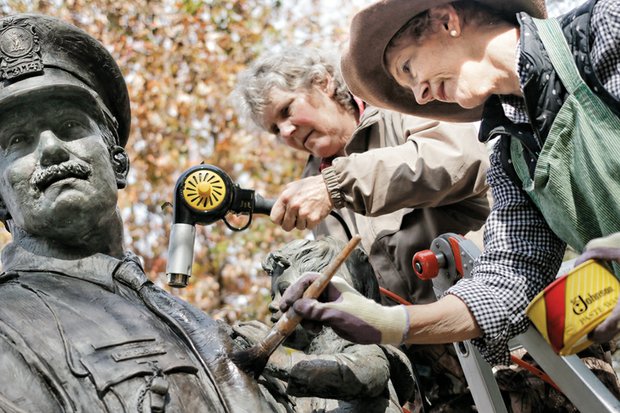 Lynda Solansky, left, and sculptor Maria J. Kirby-Smith clean the bronze Richmond Police Memorial statue in Nina F. Abady Festival Park beside the Richmond Coliseum. 
Ms. Kirby-Smith created the 8½-foot-tall statue that was placed in 1987 and pays homage to city police officers and the 28 killed in the line of duty between 1869 and 2003. A private foundation paid for the statue that depicts an officer carrying a child down steps. The artist and her friend drove up from South Carolina to wash and wax the statue Tuesday, possibly the statue’s first cleaning since it was dedicated 28 years ago. 
The cleaning was done ahead of a wreath-laying ceremony that Mayor Dwight C. Jones will lead Tuesday, Nov. 24, according to retired Officer Glenwood W. Burley, the statue’s protector. He’s now leading a push to win city approval to move the statue from its home on the 7th Street side of the park to The Carillon area of Byrd Park. 
The Carillon Civic Association, which represents people living next to the park, has publicly expressed opposition, arguing the statue would be out of place and urging city leaders to find a more suitable location. 
