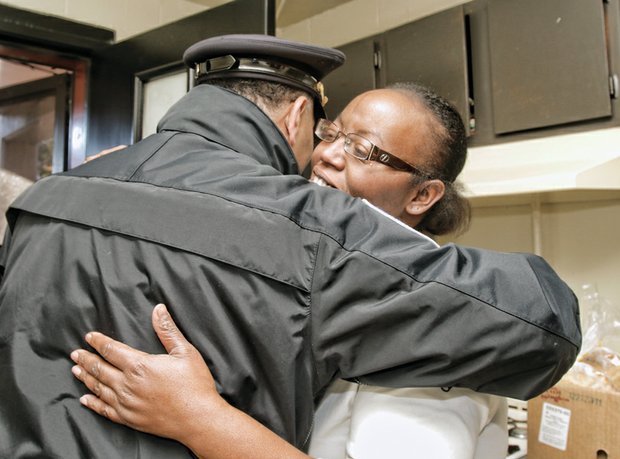 On Monday, two of Ms. Rasin’s sisters, from left, Albertina Walker and Tina Edwards, accompanied Richmond Acting Deputy Police Chief Steve Drew as he took a turkey and fixings to a family in the Richmond Dairy Apartments in Jackson Ward. Right, Chief Durham hugs Ladonna Thompson after Ms. Rasin’s sisters presented her with a Thanksgiving dinner basket.