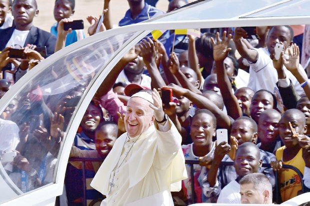 Pope Francis waves to cheering throngs of people who greeted and photographed his arrival from Kenya last Saturday at the Kololo airstrip in Kampala, Uganda. The pontiff spent two days in Uganda before continuing on to the Central African Republic.