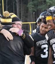 Highland Springs High School super fan Robert “Stoney” Jones, center, smiles broadly as he gives a big congratulatory hug to Springers football Coach Loren Johnson after last Saturday’s semifinal win. Quarterback Juwan “Pootie” Carter, right, and tailback D.J. Anderson will be key in the state championship match Saturday against Stone Bridge High School of Ashburn.
