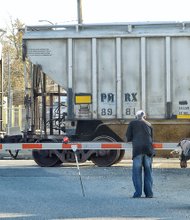 A patient pedestrian waits to push his cart filled with metal and other items across the railroad tracks. He is on his way to turn his collection into cash at the recycling plant at Stratton Metals, 900 Brook Road, on North Side. He is among hundreds in Richmond who make money collecting paper, aluminum cans and other recyclables.