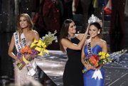 Miss Colombia Ariadna Gutierrez Arevalo, left, stands by as the Miss Universe crown is transferred Sunday to the actual winner of the pageant, Miss Philippines Pia Alonzo Wurtzbach. Host Steve Harvey mistakenly announced the runner up as the winner. He apologized, asking the loudly booing audience not to “hold it against the ladies.” Miss Universe 2014 Paulina Vega placed the crown on the head of the winner.