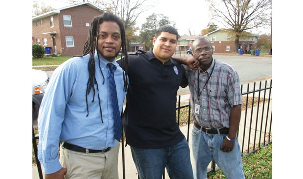 Richmond Police Officer Reynaldo Perez is flanked by Shaun Moore, left, and Jeffrey Perry, who found jobs after participating in Bridging The Gap One Human At A Time, a program the officer started. Location: Mosby Court public housing community.