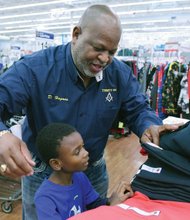 Spreading holiday cheer //
Dwight Hagans, top, helps Kyyon White choose a shirt, while Tom Graves, bottom, shops for gifts with two youngsters. Organizers expected Operation Santa Claus to provide gifts to more than 50 families. 