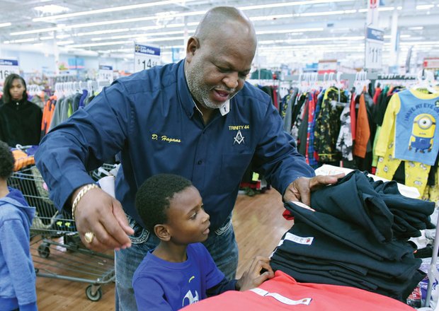 Spreading holiday cheer //
Dwight Hagans, top, helps Kyyon White choose a shirt, while Tom Graves, bottom, shops for gifts with two youngsters. Organizers expected Operation Santa Claus to provide gifts to more than 50 families. 