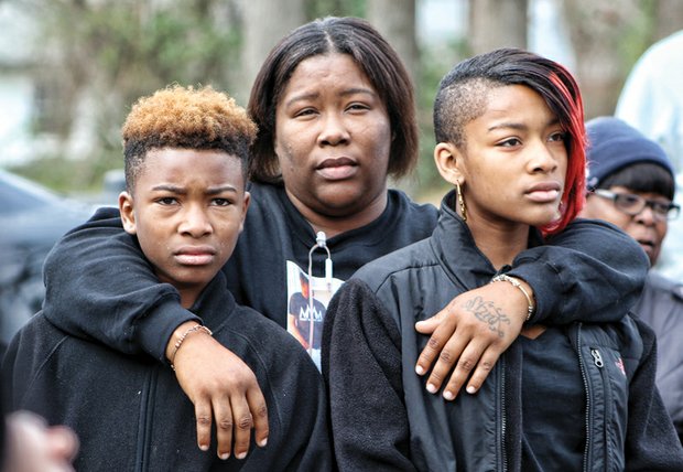 Coaches march to end violence // A previous rally against violence was held in Henrico County.
Right, Cornelia Jackson embraces her children, Joseph, left, and Shemoanee, as gunshot victims share their stories with the crowd.

Left, Coach Alex Motley holds his sign as he and Coach Anthony Grigsby lead the marchers.