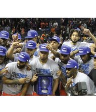 The Virginia State University Trojans conference winning basketball team strikes a victory pose Saturday with the tournament trophy after donning CIAA championship T-shirts and caps.
