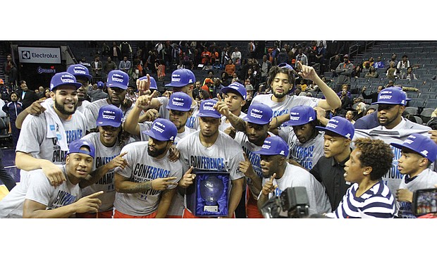 The Virginia State University Trojans conference winning basketball team strikes a victory pose Saturday with the tournament trophy after donning CIAA championship T-shirts and caps.
