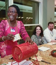 Zestful celebration  // Dora Ellis,  controller at the Richmond-based hunger relief organization FeedMore, beams as she puts a ticket in a raffle basket at Saturday night’s 16th Annual Zest Fest at the Greater Richmond Conven- tion Center. The fundraising event featured dishes by the region’s top chefs and silent and live auctions. Proceeds from the event, including raffle tickets sold by volunteers Kari Fecht, center, and Rob Giddens, will benefit FeedMore’s programs such as Meals on Wheels, Mobile Pantry and the weekend BackPack program for youngsters. 