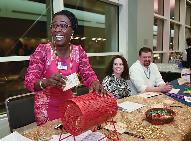 Zestful celebration  // Dora Ellis,  controller at the Richmond-based hunger relief organization FeedMore, beams as she puts a ticket in a raffle basket at Saturday night’s 16th Annual Zest Fest at the Greater Richmond Conven- tion Center. The fundraising event featured dishes by the region’s top chefs and silent and live auctions. Proceeds from the event, including raffle tickets sold by volunteers Kari Fecht, center, and Rob Giddens, will benefit FeedMore’s programs such as Meals on Wheels, Mobile Pantry and the weekend BackPack program for youngsters. 