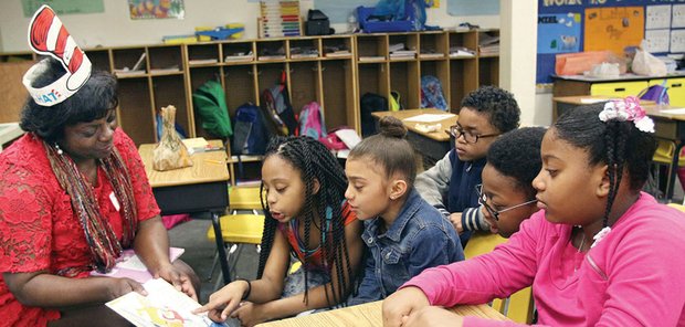 Making Reading Fun // Volunteer Carolyn Hawley of the Richmond Alumnae Chapter of Delta Sigma Theta Sorority wears her Dr. Seuss hat as she engages third-graders at Overby-Sheppard Elementary School in reading last Friday. She was among a cadre of volunteers who participated in special programs and activities at nine Richmond elementary schools for in celebration of Read Across America. Local and national efforts were designed to motivate children and teens to read. The National Education Association organizes the annual initiative.