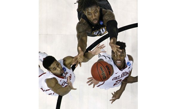 Virginia Commonwealth University’s Mo Alie-Cox, center, tries to reach over University of Oklahoma’s Isaiah Cousins, left, and Buddy Hield for a rebound during Sunday’s NCAA Tournament second round game in Oklahoma City.