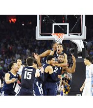 Ecstatic teammates mob Villanova’s Kris Jenkins (2) after he shot the winning three-point basket to upset the University of North Carolina 77-74 and secure his school’s first NCAA men’s Division I hoops championship since 1985. Just four-tenths of a second were left on the clock when the game-ending shot left his hands. His shot came just 4.3 seconds after UNC’s Marcus Paige hit an off-balance 3-pointer to tie the game, seemingly sending it to overtime. 